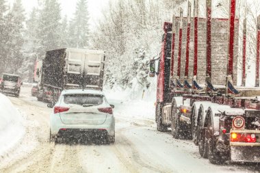 Trafik sıkışıklığı, arabalar ve kamyonlar ağır kar Blizzard sırasında kış ormanı yol dağ geçişi yavaş hareket eden araçların tüm logolar markalar kaldırıldı 