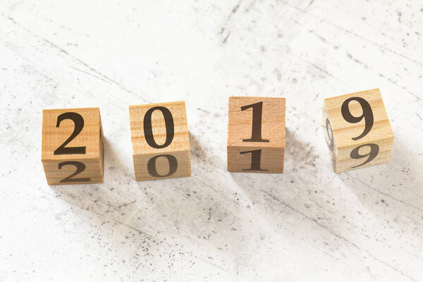 Four wooden cubes with number 2019 on white working board.