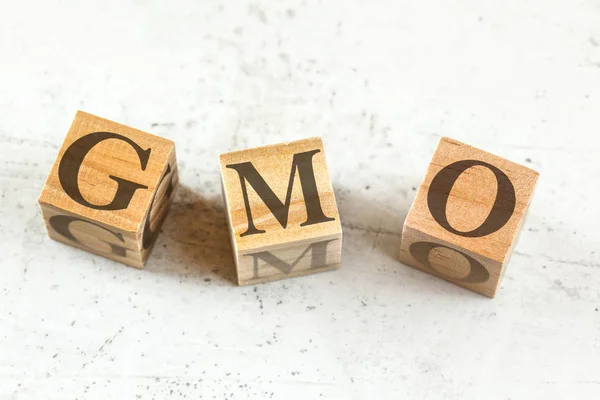 Três cubos de madeira com letras OGM significa organismo geneticamente modificado na placa branca . — Fotografia de Stock