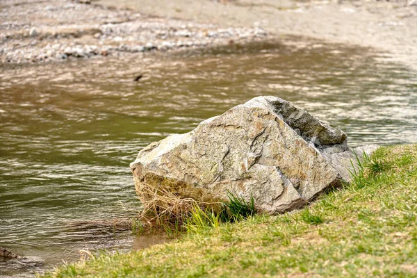 Piedra de roca grande en el lado de hierba del río . —  Fotos de Stock