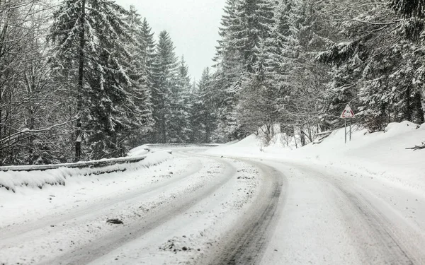 Curve on forest road covered with snow, more falling, dangerous driving conditions — Stock Photo, Image