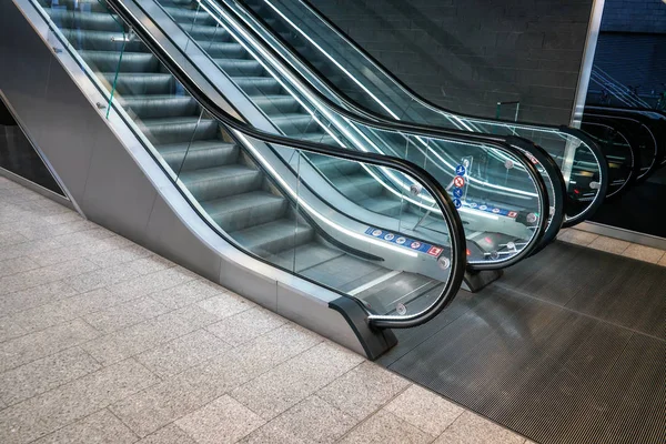 Planta baja cerca de escaleras mecánicas vacías iluminadas en edificio moderno —  Fotos de Stock