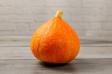 Gri ahşap masada kırmızı kuri kabak (Hokaido kabak).