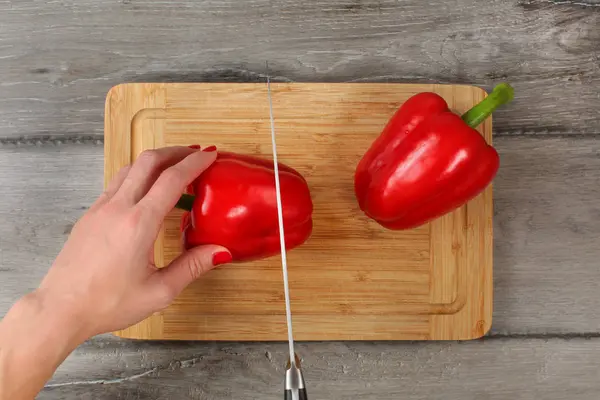 Tabletop view - woman cutting red bell pepper on chopping board — Stock Photo, Image