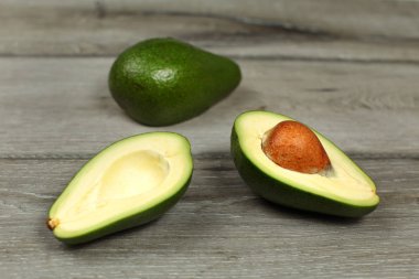 İki avokado, bir ikiye kesilmiş, tohum görünür, gri ahşap masa t