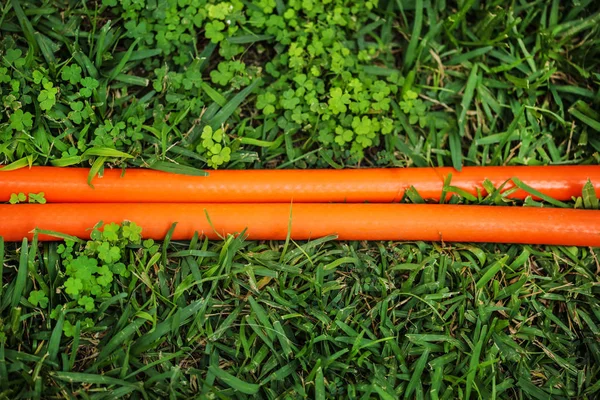 Tubo flessibile arancione brillante (due linee) in prato verde. Vista dall'alto. A — Foto Stock