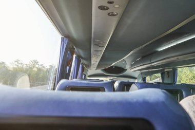Otobüs otobüsünde boş mavi koltuk satır, pencere arkasında güneşli bir gün, arkadan görünümü