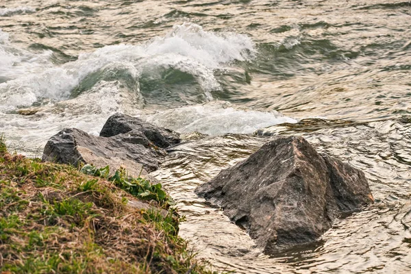 Eau coulant près de la roche sur le rivage, formant une petite vague dans la rivière, éclairée par la lumière du coucher du soleil du soir — Photo