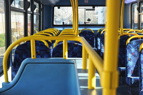 El sol brilla en el interior vacío del autobús de dos pisos de Londres, rieles amarillos y asientos azules —  Fotos de Stock