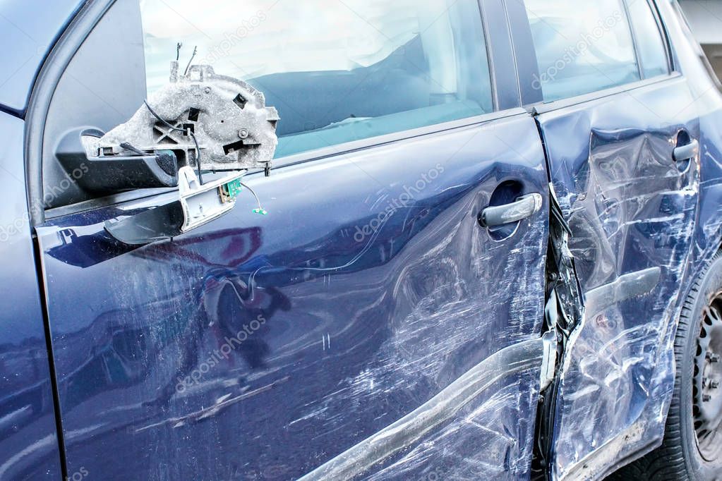 Crashed car, detail on side mirror and door - metal plates deformed after accident hit.