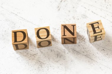 Beyaz çalışma tahtası üzerinde kelime done ile dört ahşap küpler.