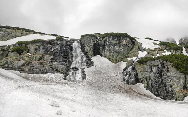 スロバキアのハイタトラスの滝スコック、曇りの春の日の間に、汚れた雪はまだ地面のほとんどをカバーしています — ストック写真