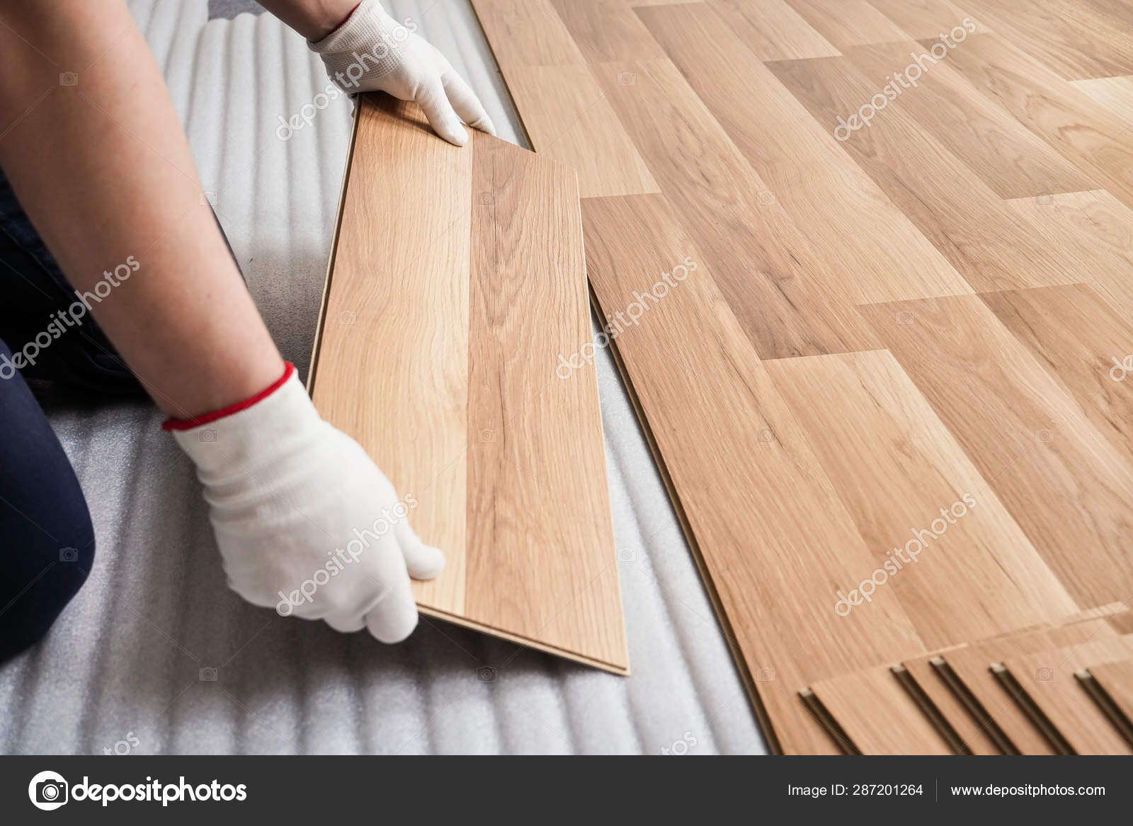 Installing laminated floor, detail on man hands with white gloves