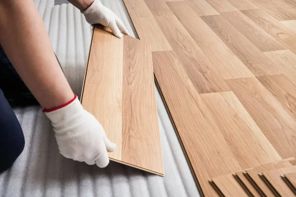 Laminált padló telepítése, részlet az ember kezét, fehér kesztyű berendezési fa csempe, fehér hab alapréteg — Stock Fotó