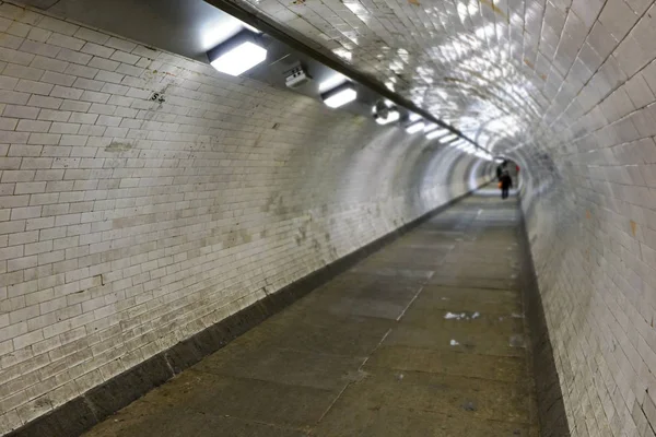 Interno del tunnel pedonale di Greenwich che collega entrambi i lati di Londra sotto il Tamigi, illuminato da luci al neon, foto grandangolare con pedoni sfocati in lontananza — Foto Stock