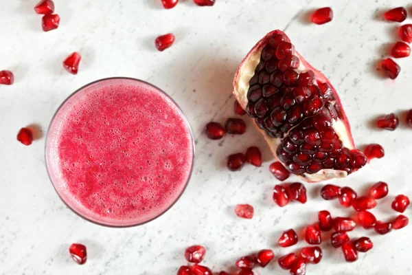 Pembe nar smoothie ile Cam, daha fazla çilek ve yanında beyaz taş tahta meyve parçası, yukarıdan görünümü