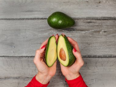 Masa üstü görünümü, avokado c iki yarısı tutan genç kadın elleri