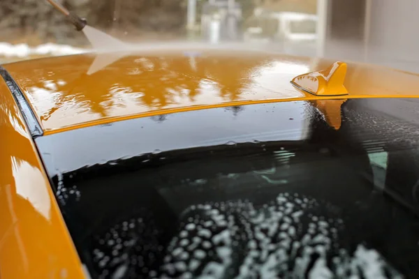 Horní část žlutého vozu omytá v mycích vodách, voda tekoucí na střeše a s — Stock fotografie