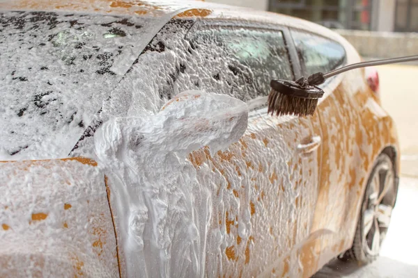 Yellow car washed in self service carwash. Shampoo  spraying to — Stock Photo, Image