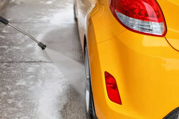 Rueda trasera de coche amarillo lavado con agua de chorro en auto servir coche —  Fotos de Stock