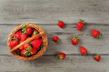 Tabletop view basket with strawberries, some of them spilled on  clipart