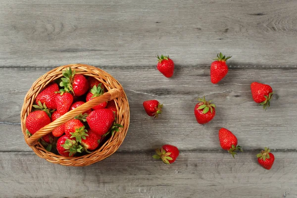 Cesta de vista de mesa con fresas, algunas de ellas derramadas — Foto de Stock