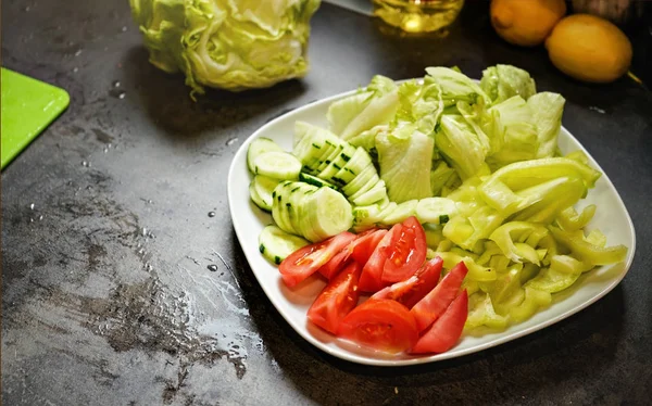 Нарізати помідори, огірки та айсберг на темній кухні — стокове фото