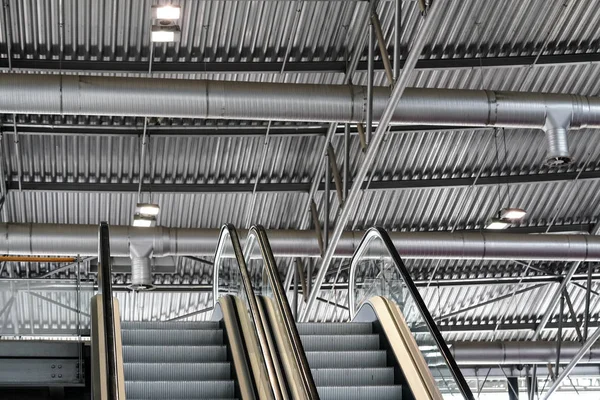 Inside roof of metal hall, elevators leading to second floor