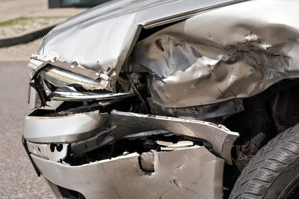 Voiture écrasée après un accident de la route, détail sur feu avant démoli et plaques métalliques — Photo