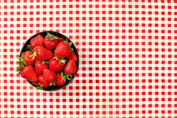 Vista de la mesa, pequeño cuenco de cerámica negra de fresas en c rojo — Foto de Stock