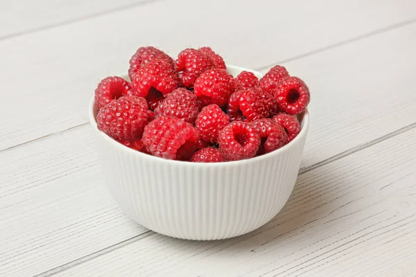 Small white ceramic bowl full of freshly picked raspberries, lig — Stock Photo, Image