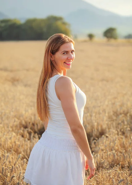 Молодая женщина в белом платье оглядывается назад через плечо, смайлик — стоковое фото