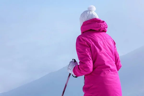 後ろから見て、ピンクのスキージャケットの若い女性、彼女のhの極 — ストック写真