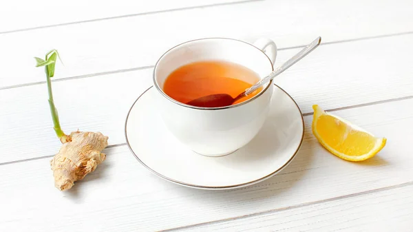 White porcelain cup with hot amber tea, silver spoon in it, dry — Stock Photo, Image