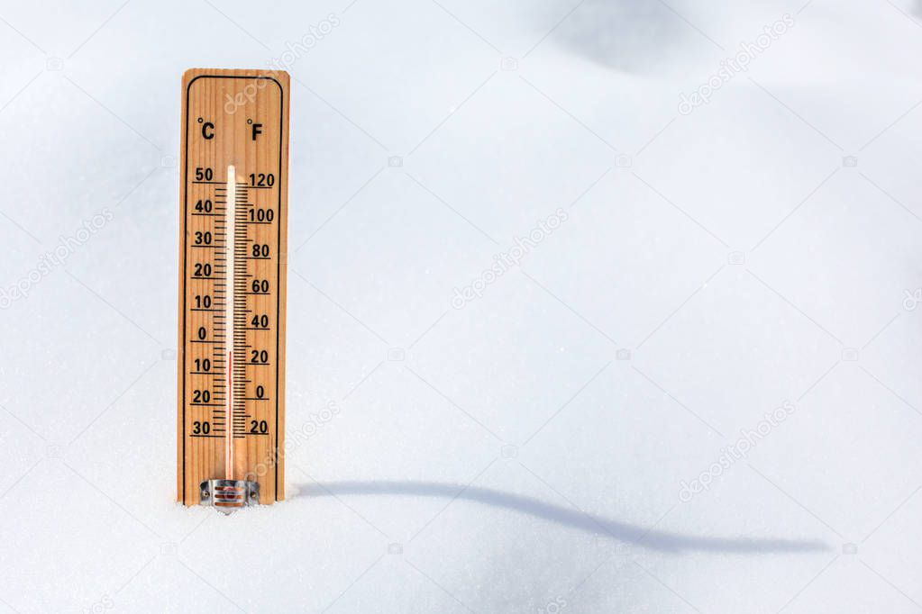 Wooden thermometer standing in snow, showing low temperature, sp