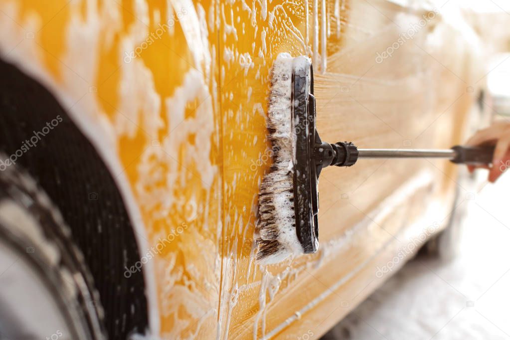 Yellow car washed at self serve carwash, detail on brush cleanin