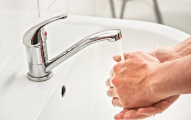 Musluğun altında ellerini yıkayan bir adam. Kişisel hijyen kavramı, covid-19 koronavirüs salgınında kullanılabilir