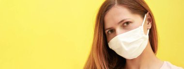 Beyaz evdeki genç kadın pamuk suratlı virüs maskesi, sarı arka planlı geniş pankart, sol tarafta mesaj için yer var. Coronavirus covid-19 salgın önleme kavramı
