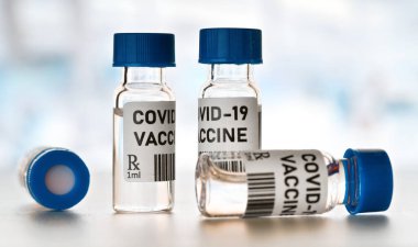 Coronavirus Covid-19 aşı konsepti - beyaz masa üzerinde mavi başlıklı küçük cam şişeler, yakın plan detay (kendi tasarımı - sahte barkod)