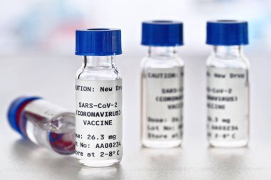 Coronavirus sars-CoV-2 aşı konsepti, beyaz masanın üzerinde mavi başlıklı küçük şişeler (çıkartma sahte verili kendi tasarımıdır - gerçek bir ürün değil)
