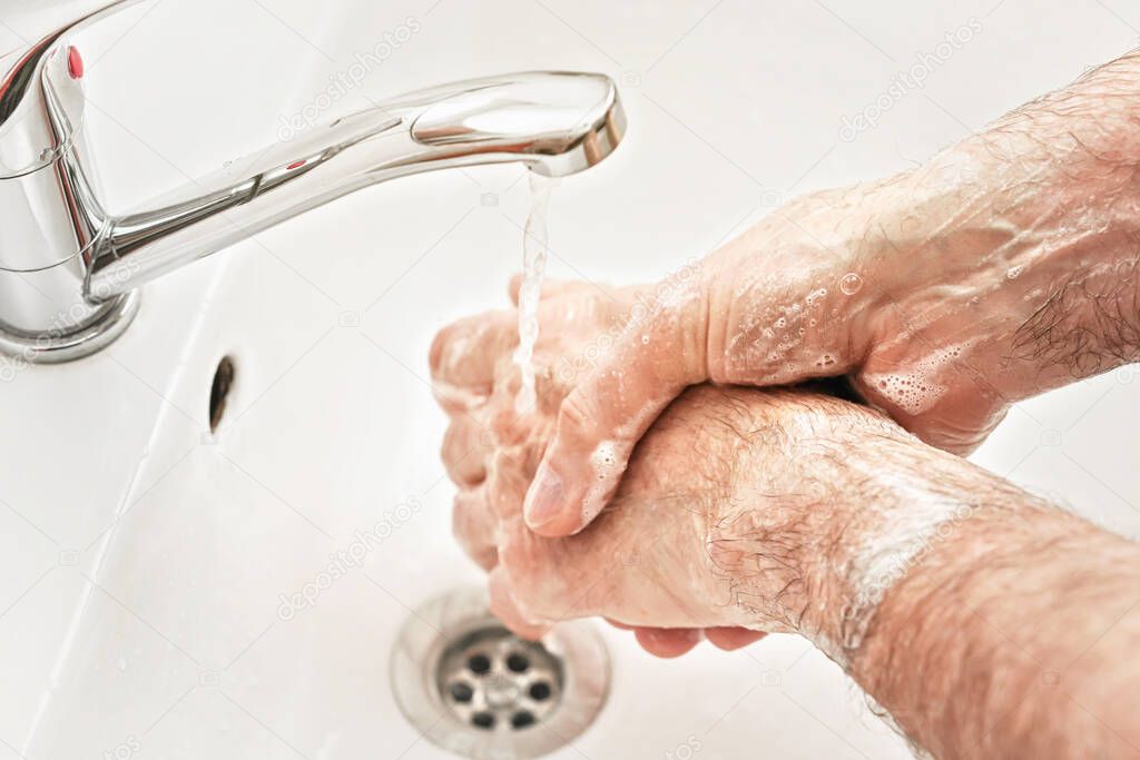 Senior elderly man his hands with soap under tap water faucet, detail photo. Can be used as hygiene illustration concept during coronavirus / covid19 outbreak prevention