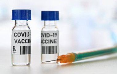 Coronavirus Covid-19 aşı konsepti - beyaz masa üzerinde mavi başlıklı küçük cam şişeler, yakın plan yeşil turuncu şırınga (kendi tasarımı - sahte barkod)