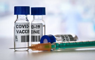 Coronavirus Covid 19 aşı konsepti - beyaz masa üzerinde mavi başlıklı küçük cam şişeler, yakın plan yeşil turuncu şırınga (kendi tasarımı - sahte barkod)