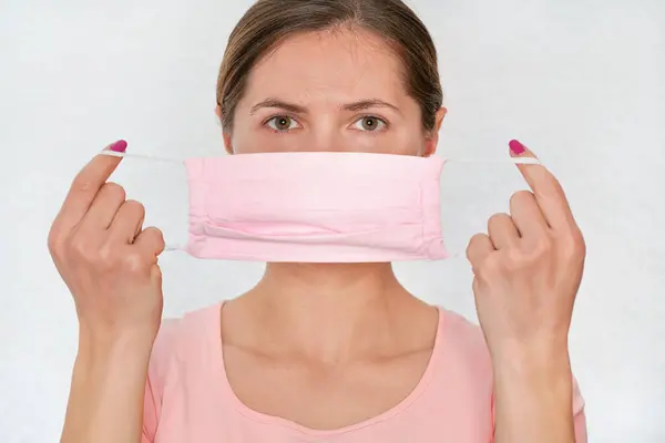 ピンクの綿の家を置く若い女性は 上のウイルス口の顔マスクを作った 彼女の前にそれを保持 白い背景に肖像画 コロナウイルスCovid 19発生防止中に使用することができます — ストック写真
