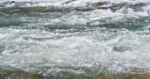 Rapid spring river fluindo sobre rochas no dia ensolarado, formando ondas de água branca, detalhe close-up - abstrato natureza fundo — Fotografia de Stock