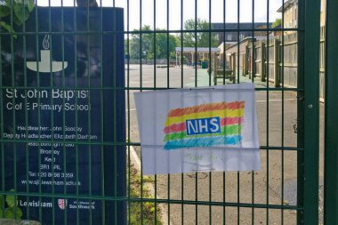 Londra, Birleşik Krallık - 04 Mayıs 2020: Coronavirus covid 19 salgını sırasında St. John Baptist ilkokulunun çitlerinde sergilenen NHS 'ye teşekkür notuyla el çizimi gökkuşağı