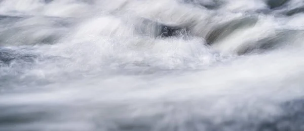 Foto de longa exposição - água fluindo sobre rochas tudo suave, apenas algumas gotas de água em foco — Fotografia de Stock