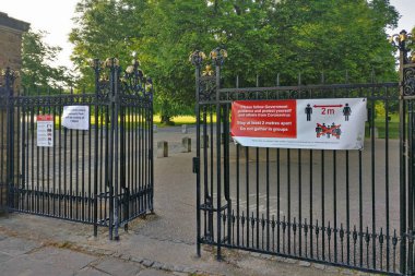 Londra, Birleşik Krallık - 08 Mayıs 2020: Coronavirus covid 19 nedeniyle Greenwich Park 'taki çitlerde virüs önleme tavsiyesi güvenlik işareti. Salgın sırasında birçok halka açık yer kısıtlanmıştır.
