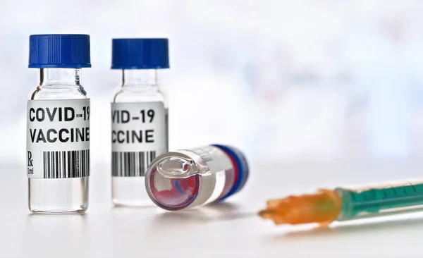 コロナウイルスCovid 19ワクチンのコンセプト 白いテーブルの上に青いキャップを持つ小さなガラスのバイアル クローズアップの詳細近くの緑のオレンジの注射器 自分のデザイン ダミーバーコード — ストック写真
