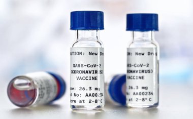 Coronavirus Covid 19 aşı konsepti - beyaz masa üzerinde mavi başlıklı küçük cam şişeler, yakın plan detay (sahte verili kendi çıkartma tasarımı - gerçek ürün değil)